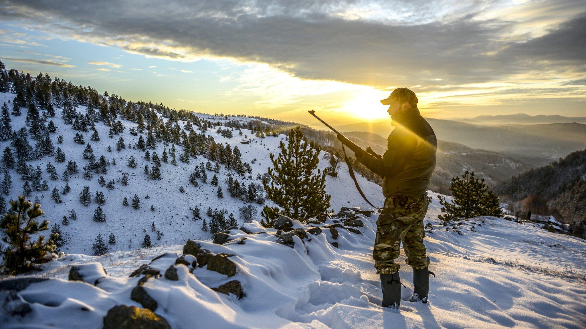 A hunter looks over a snowy mountain