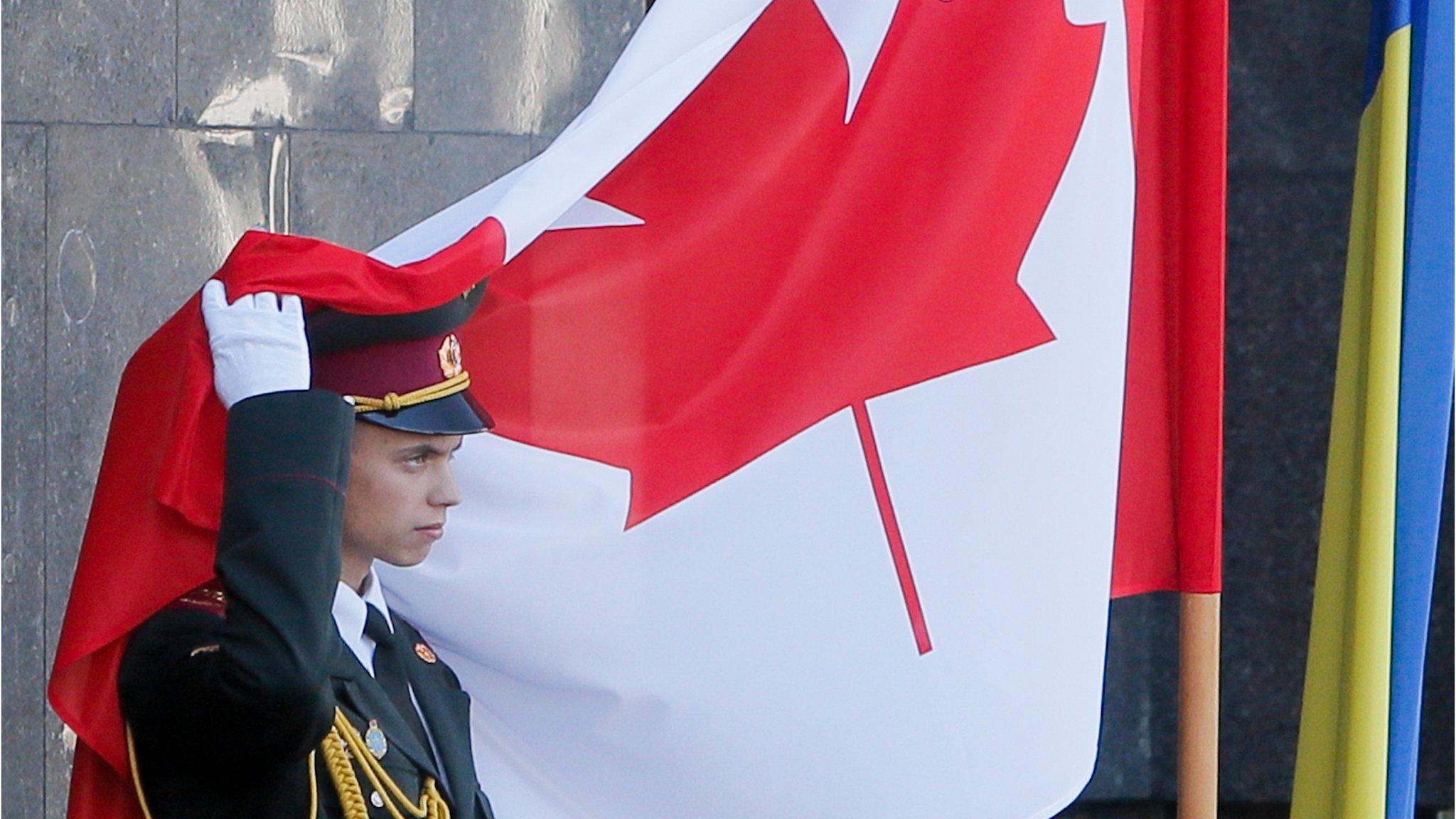 An Ukrainian soldier takes away the Canadian flag from his hat during a welcome ceremony in Kiev, Ukraine, Monday, July 11, 2016