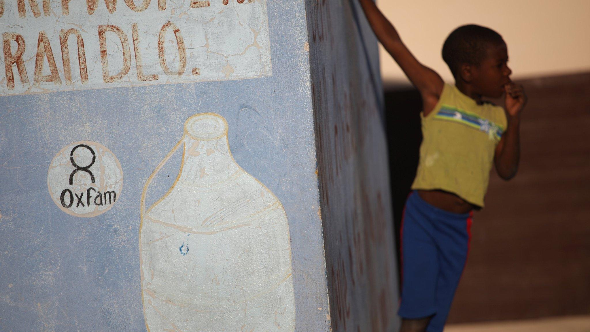 Boy stands next to Oxfam kiosx