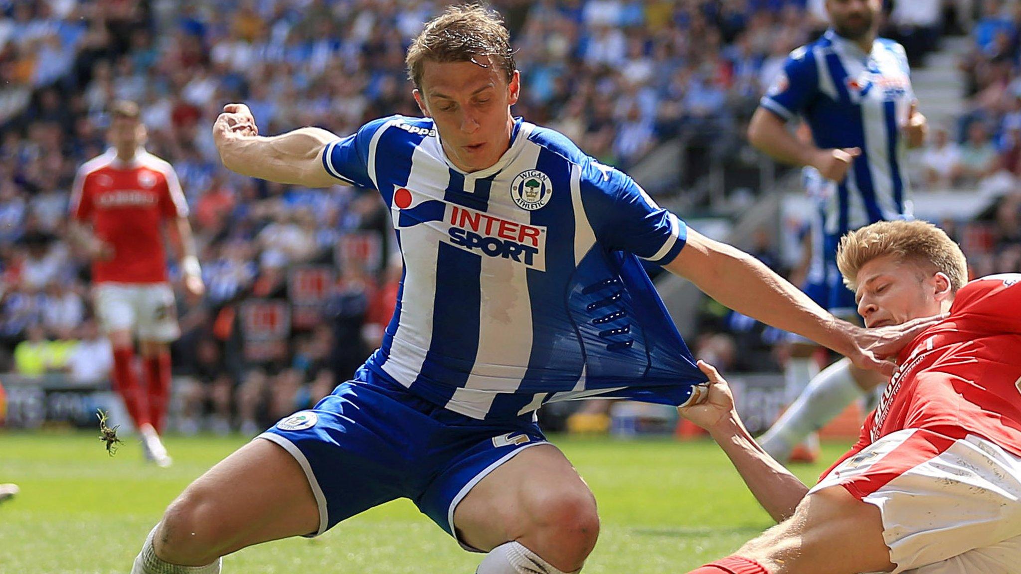 Wigan Athletic loan defender Stephen Warnock is challenged by on-loan Barnsley winger Lloyd Isgrove