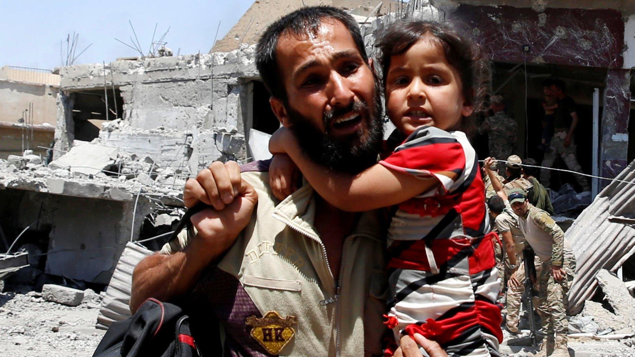 A man displaced by fighting between Iraqi forces and Islamic State militants carries his daughter in Mosul's Zanjili district (7 June 2017)