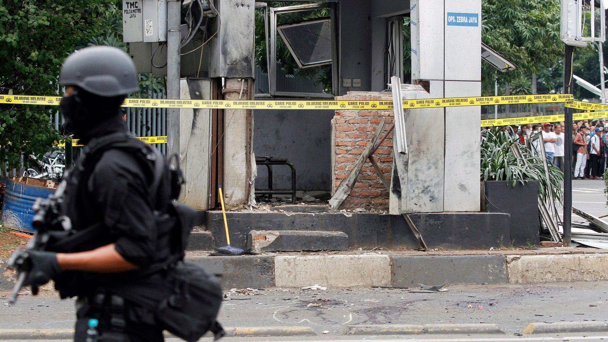 policeman and police tape hold back a crowd in Jakarta