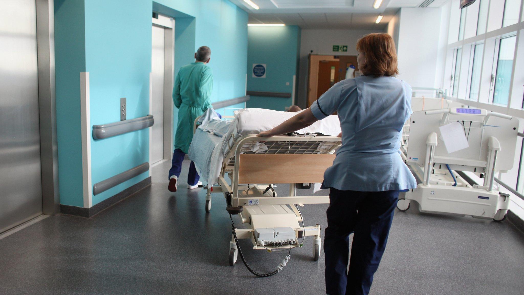 A bed-ridden patient being moved in a hospital corridor