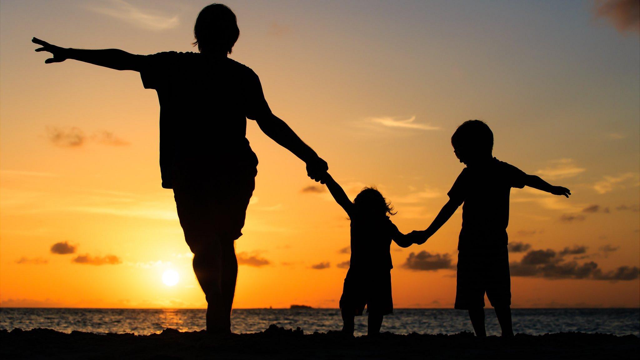 Family walk along a beach at sunset