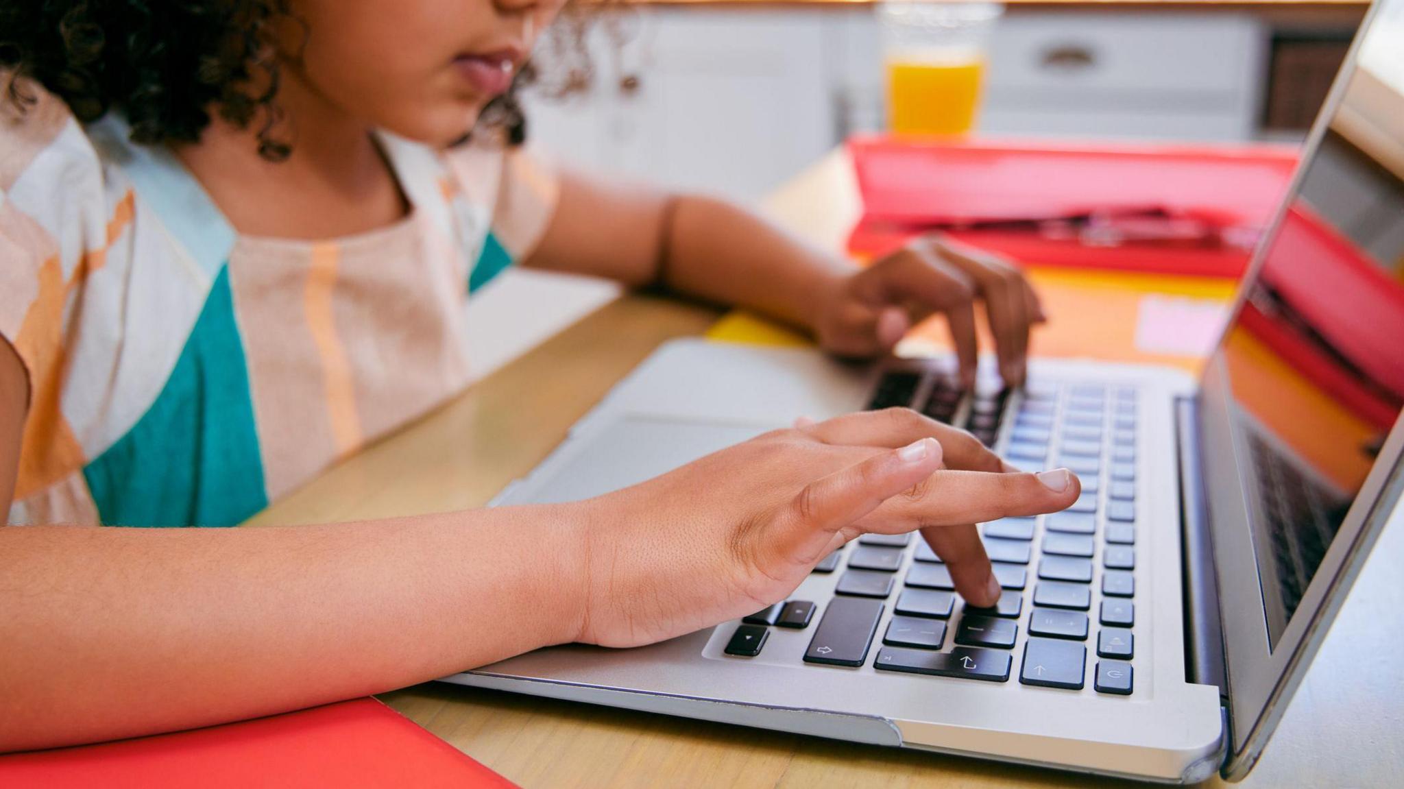 A child taps at a laptop on a breakfast table