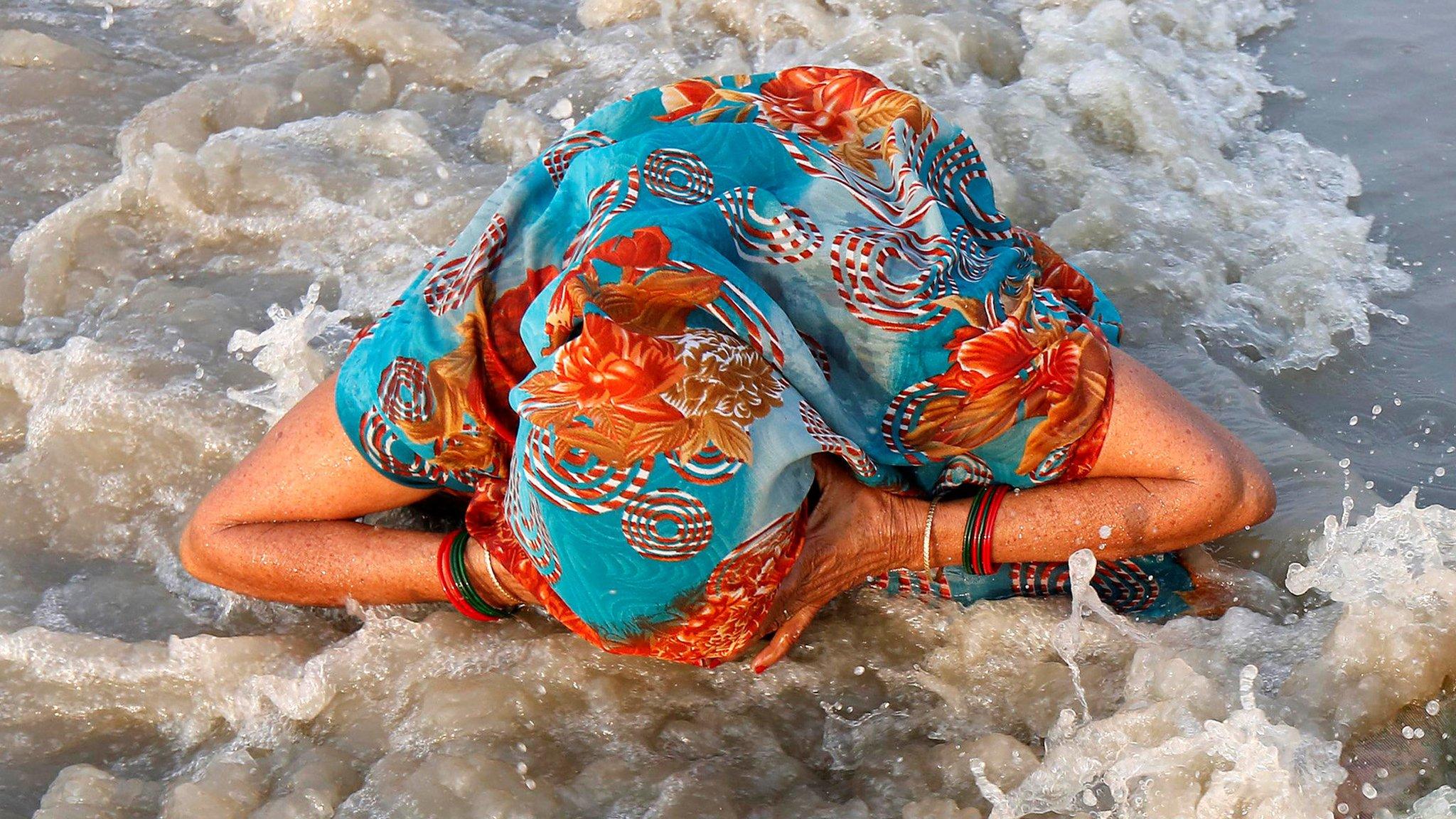 A Hindu pilgrim takes a dip at the confluence of the river Ganges and the Bay of Bengal on the occasion of "Makar Sankranti" festival at Sagar Island, south of Kolkata, India, 14 January 2017