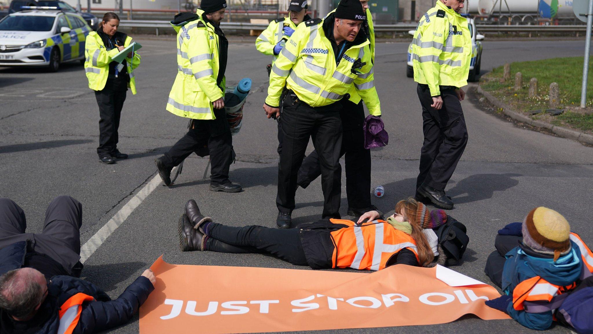 Police officers look at activists from Just Stop Oil taking part in a blockade at the Kingsbury Oil Terminal, Warwickshire