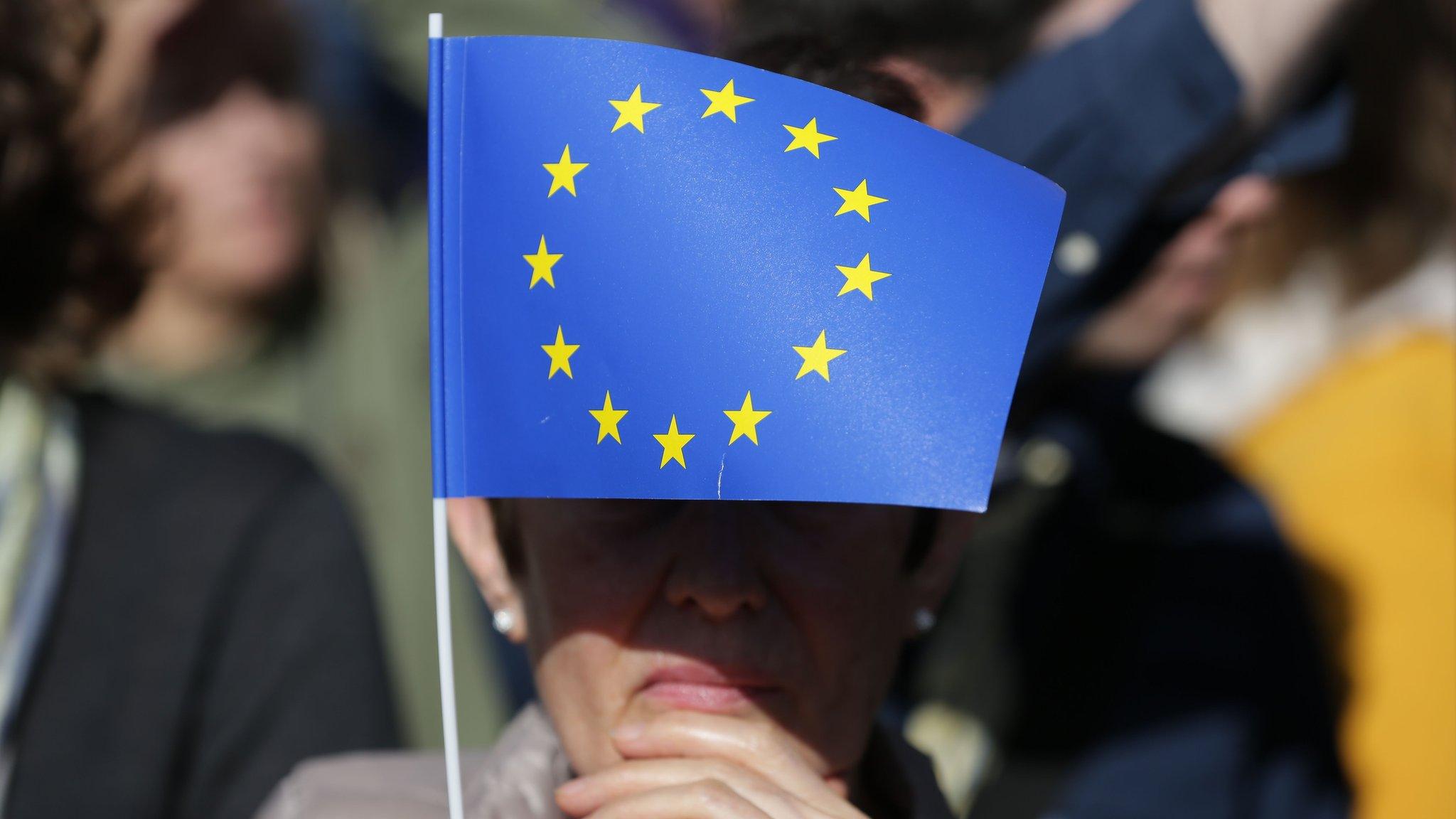 A woman flies a small EU flag in Parliament Square during an anti-Brexit, pro-European Union march in central London on March 25, 2017