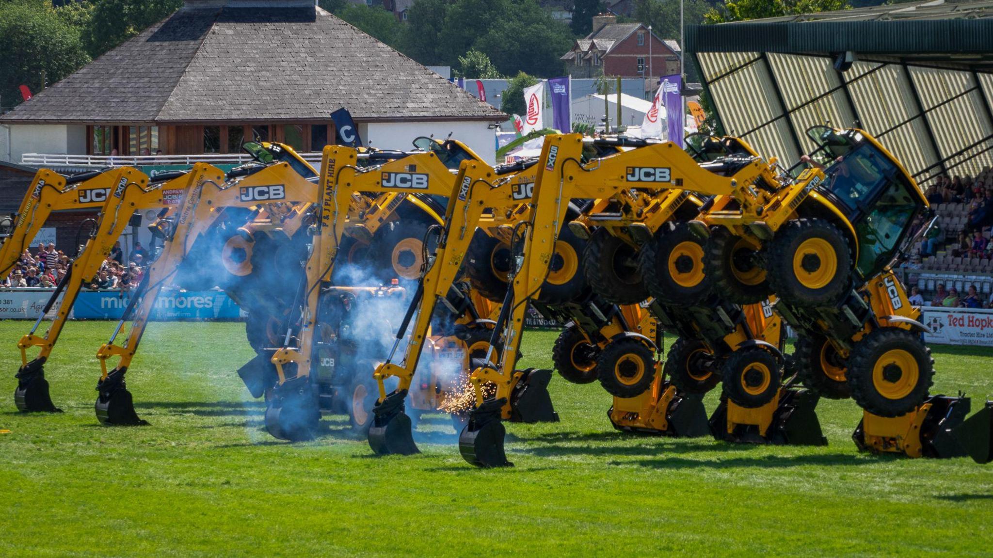 Tractors pitched on their diggers with a vehicle driving fireworks beneath