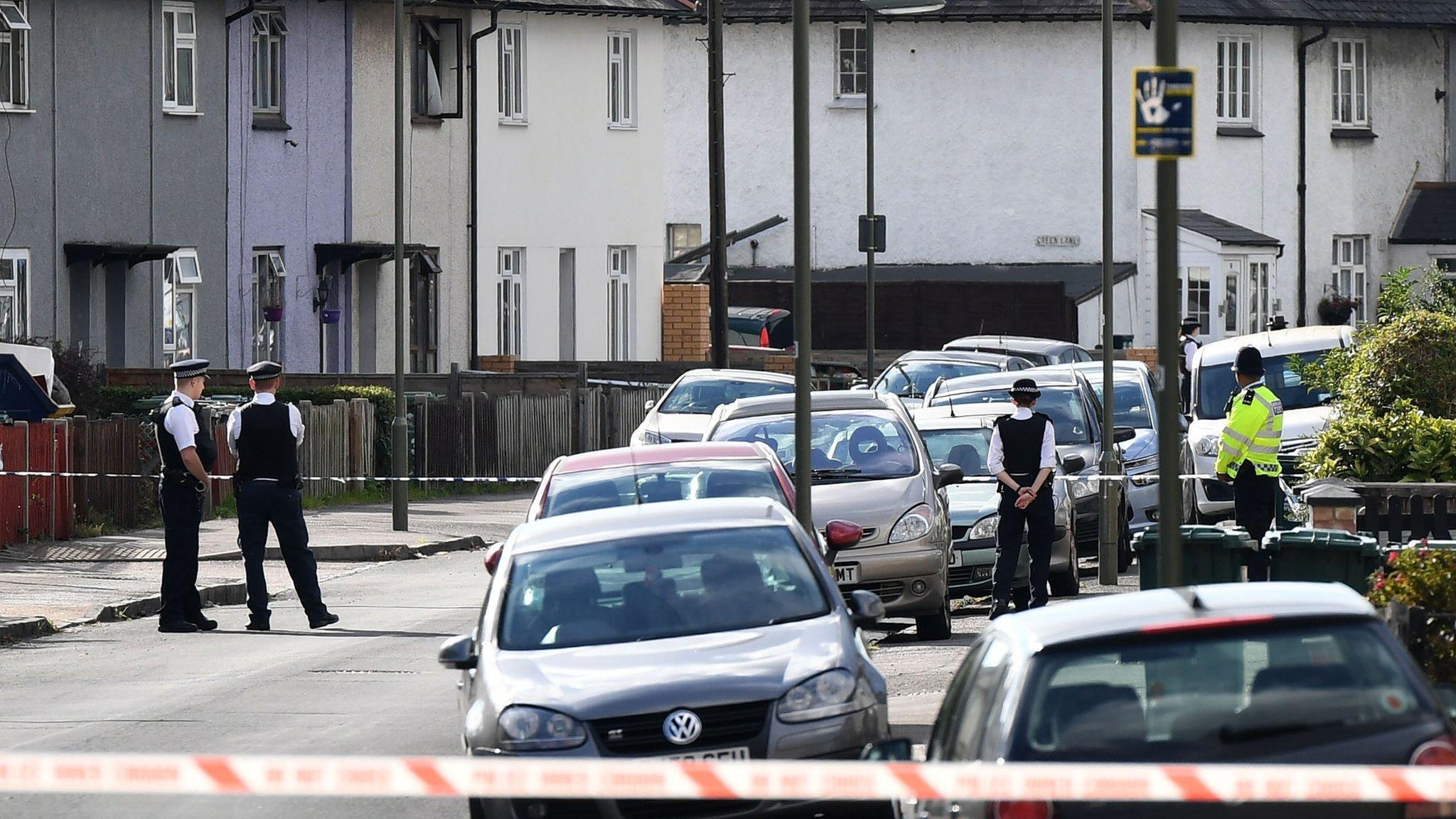 Police stand guard at a cordon during a raid on a home in Surrey