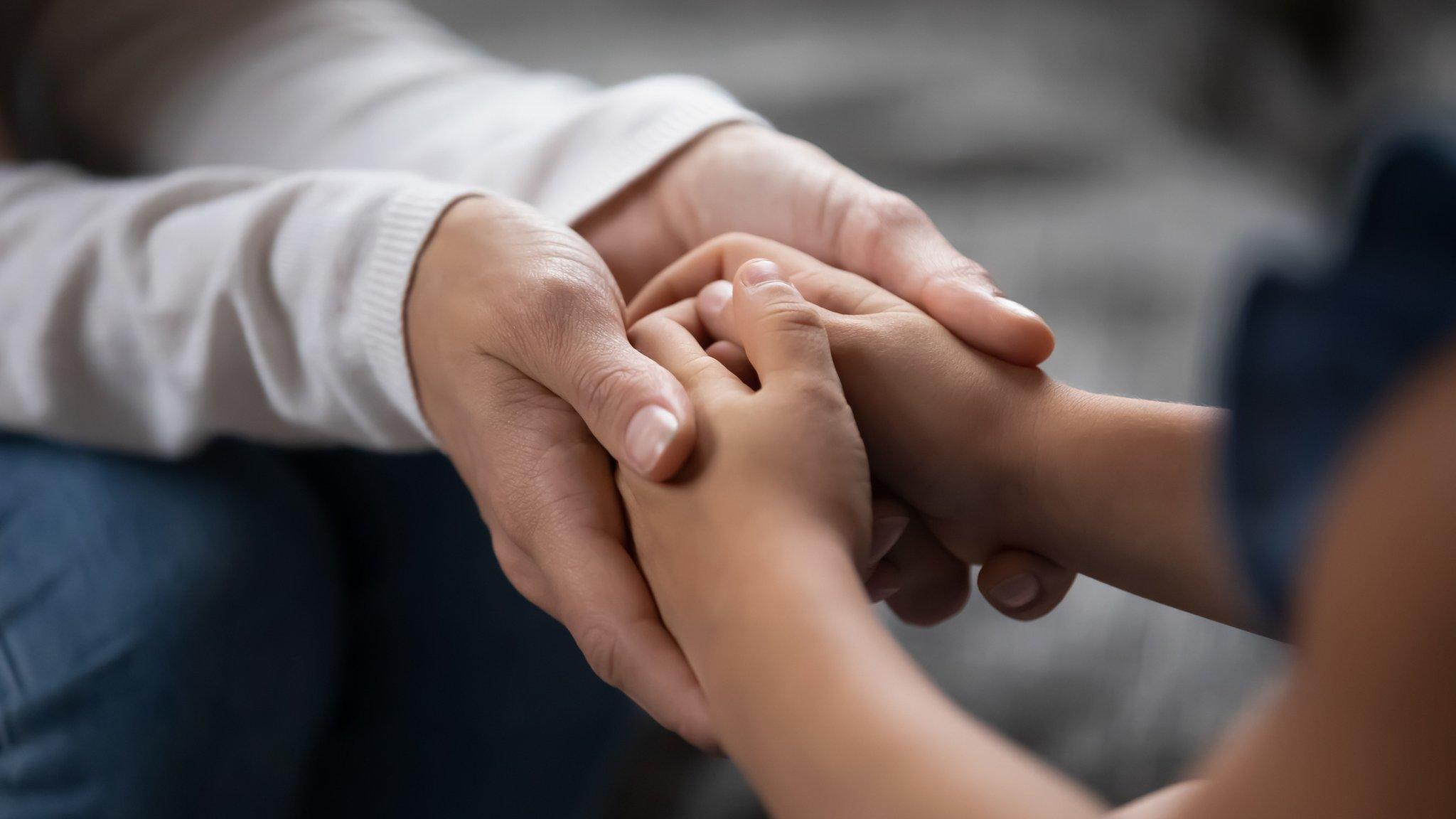 An adult and child holding hands