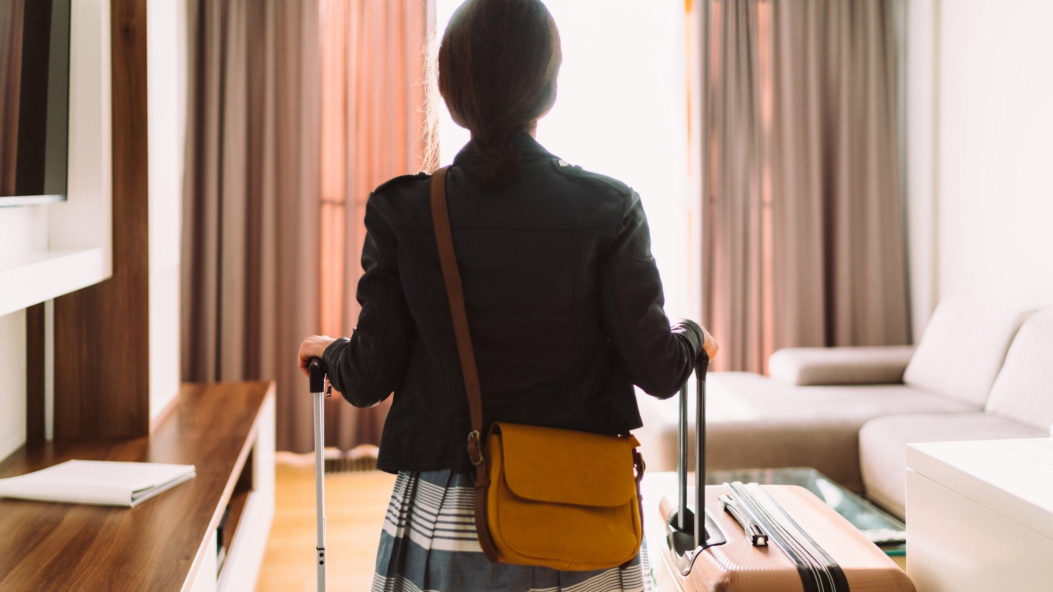 Woman entering hotel room with suicases