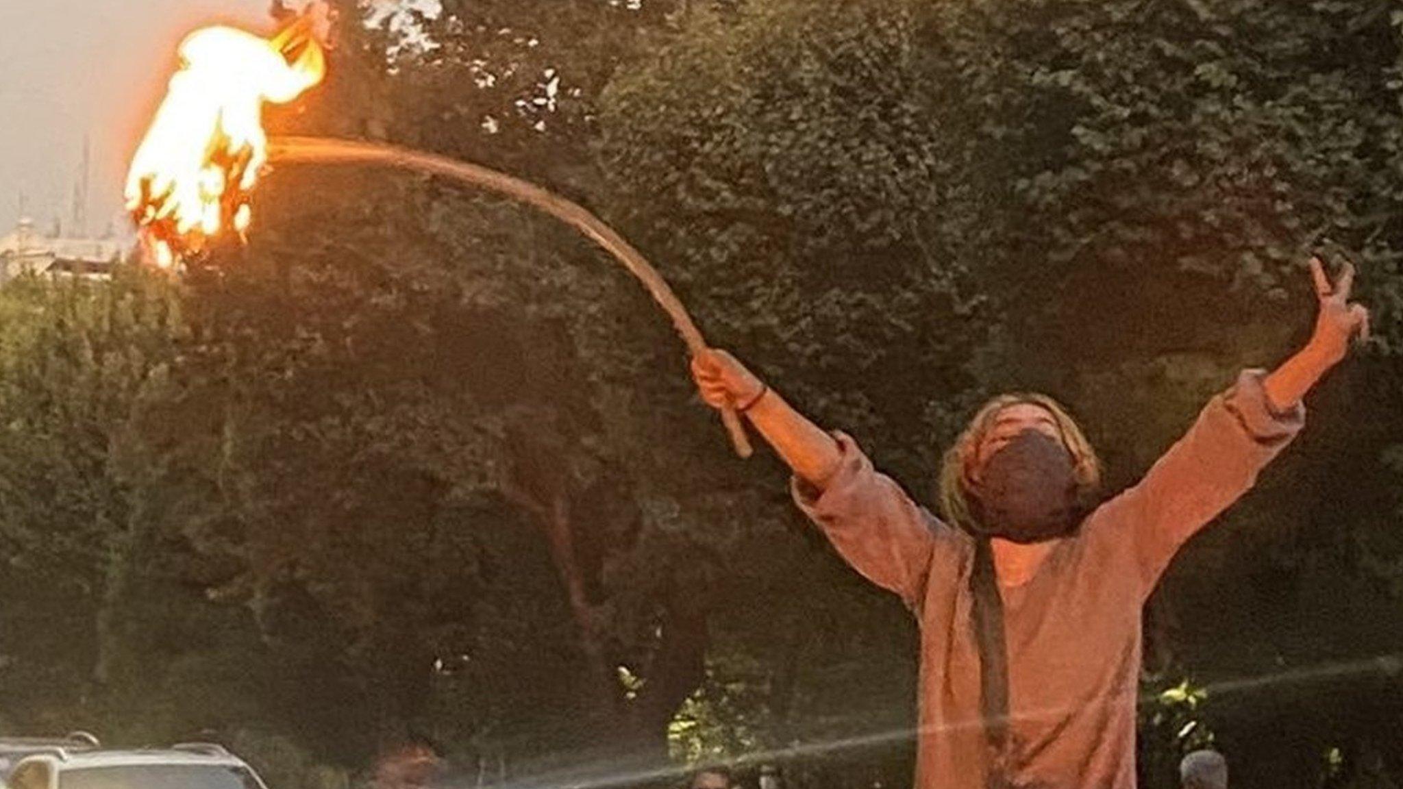 A woman stands on top of a car bonnet and sets her headscarf on fire on 19 September 2022 in central Tehran during protests for Mahsa Amini