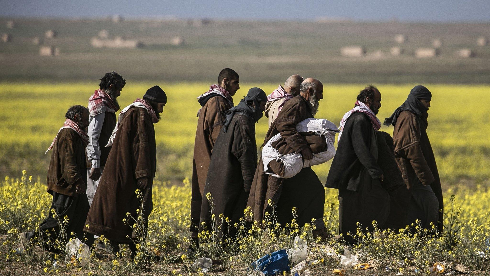 Suspected militants evacuated from the last IS-held village of Baghuz walk towards a screening area (6 March 2019)