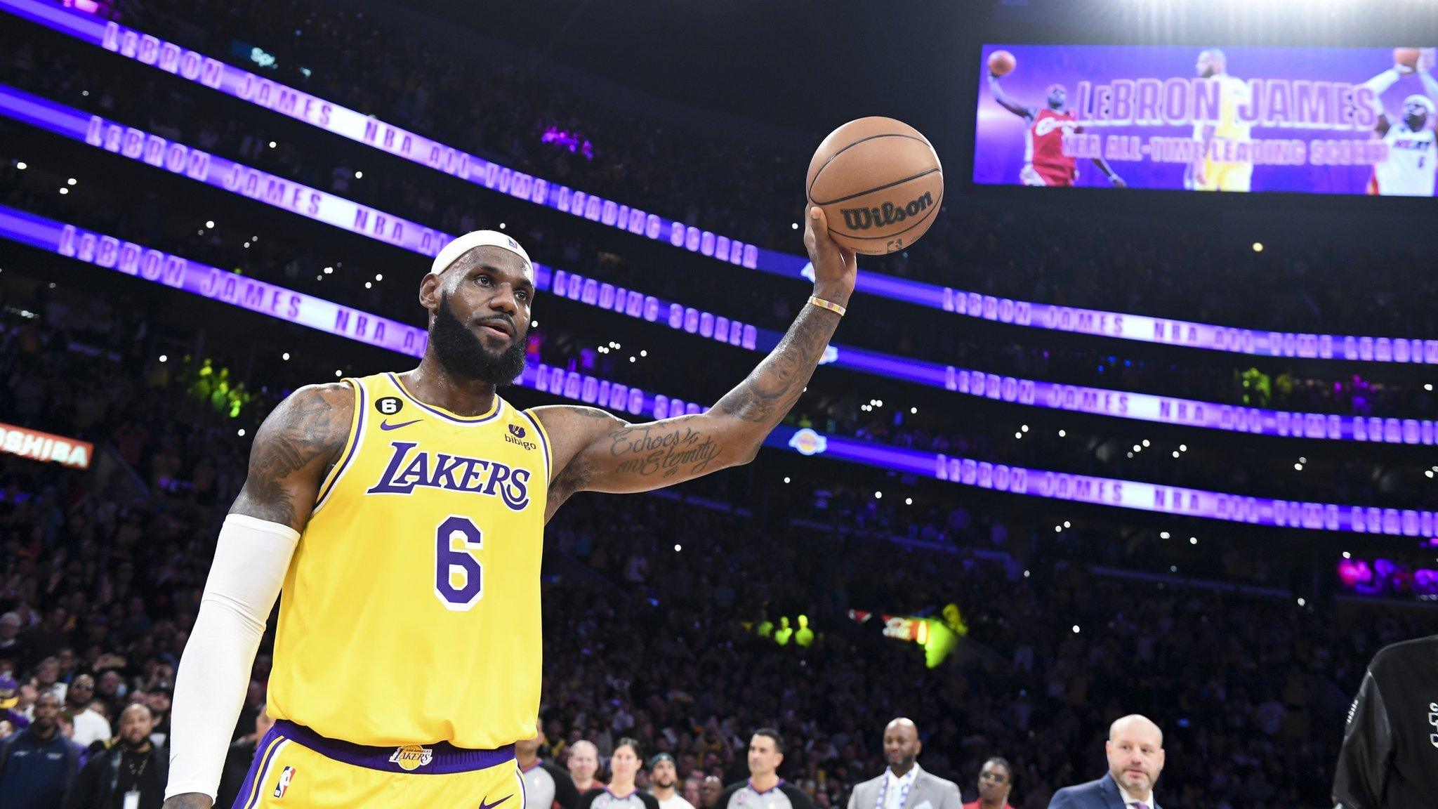 Lebron James holding a basketball in the air after breaking the NBA scoring record