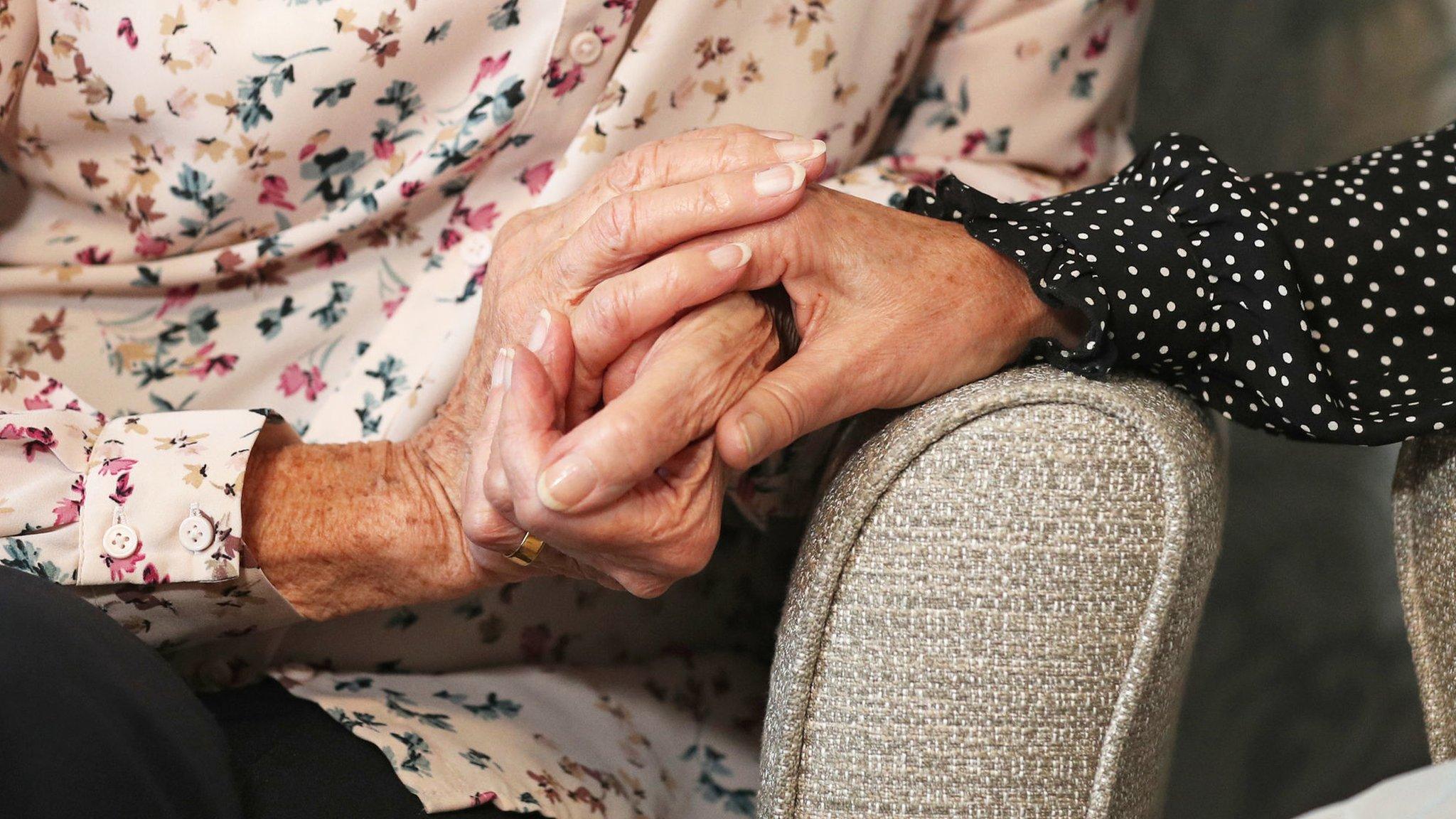 Two people holding hands on armchairs