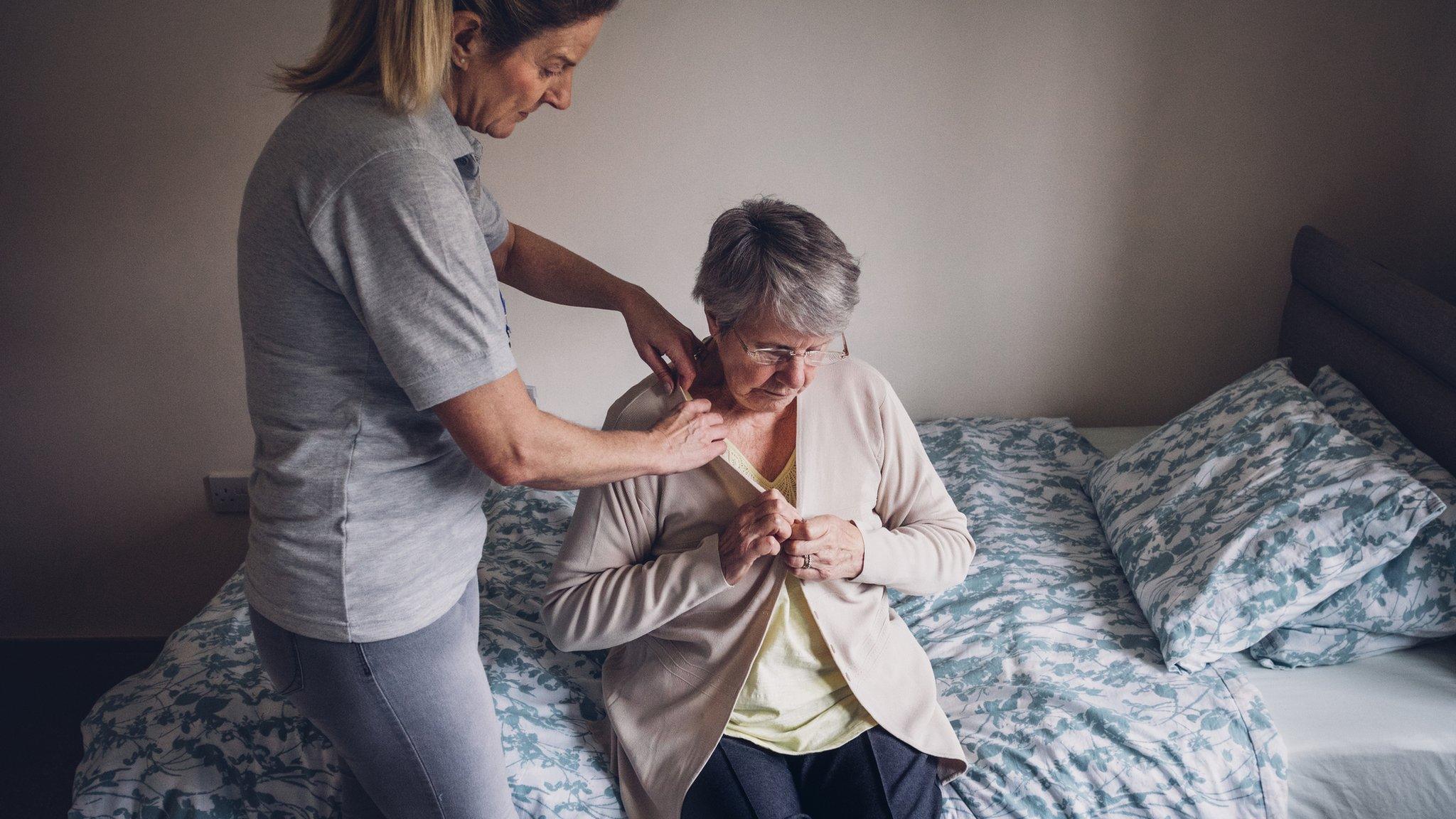 A pensioner being helped to dress