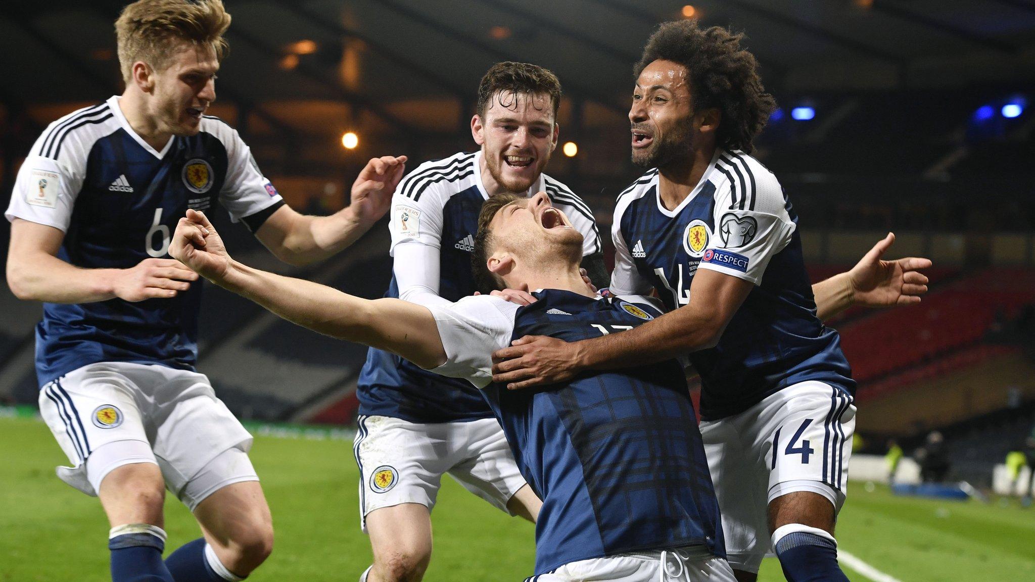 Chris Martin is mobbed after firing the late winner against Slovenia