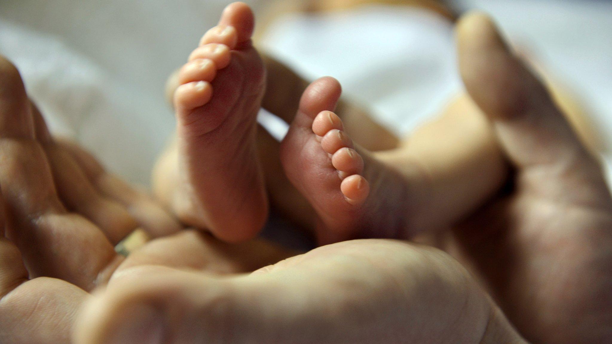 Baby's feet cradled in parent's hands