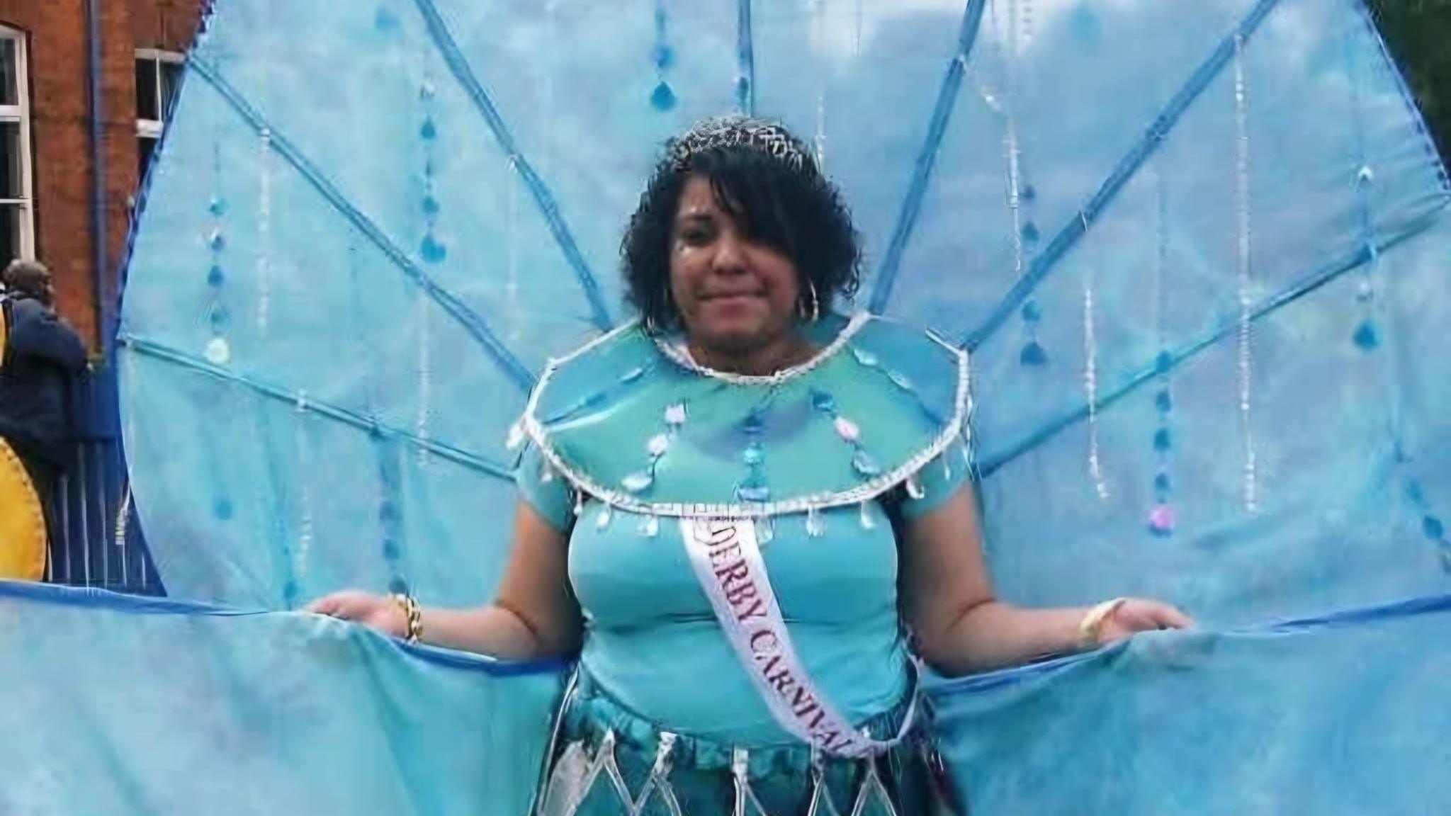A woman in a big blue costume wearing a sash