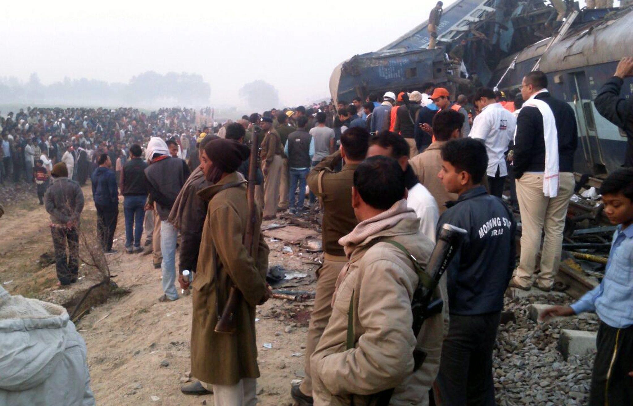 Hundreds of people stand next to the overturned carriages in northern India