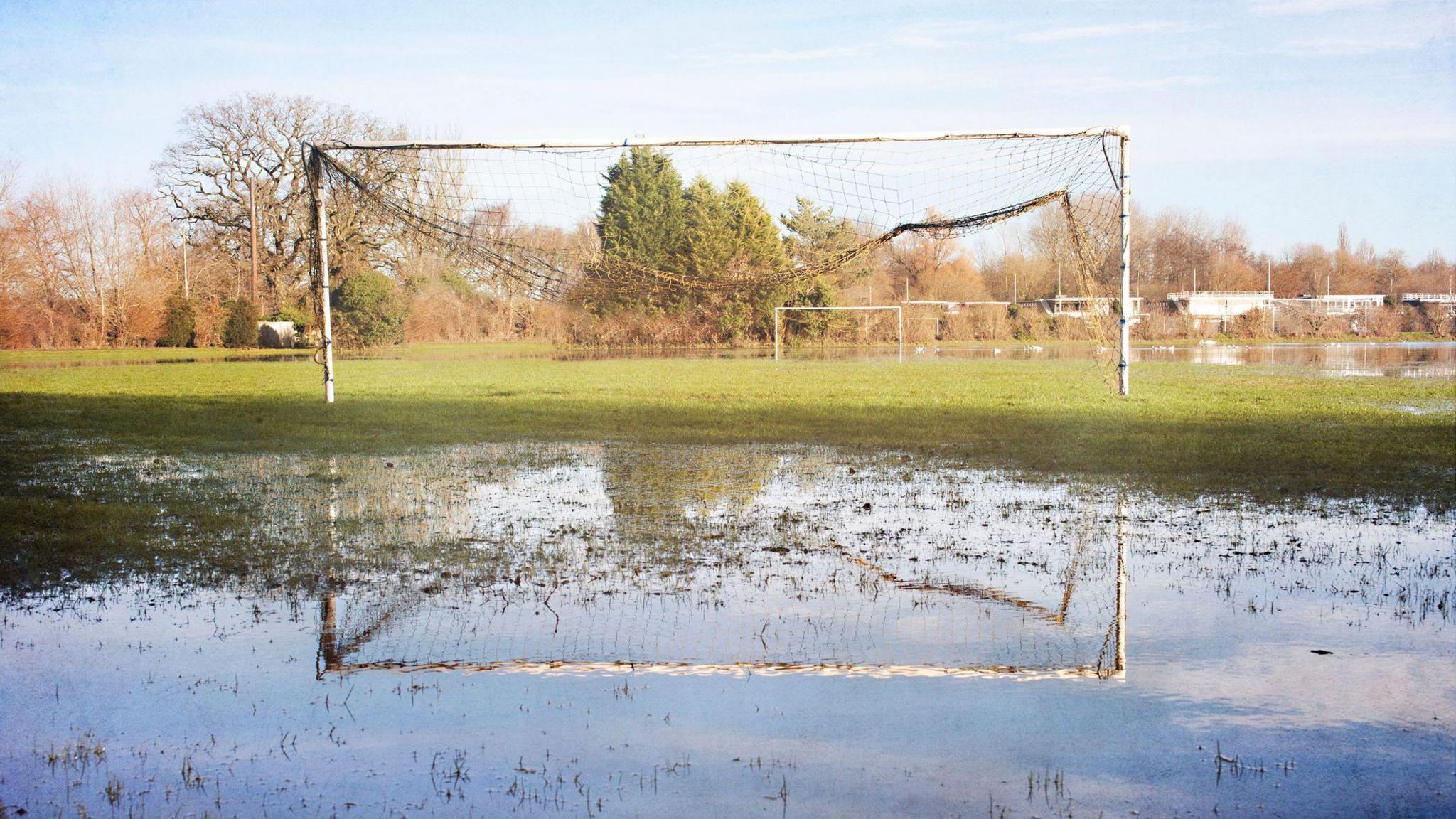 Waterlogged pitch with goalposts being reflected in the water