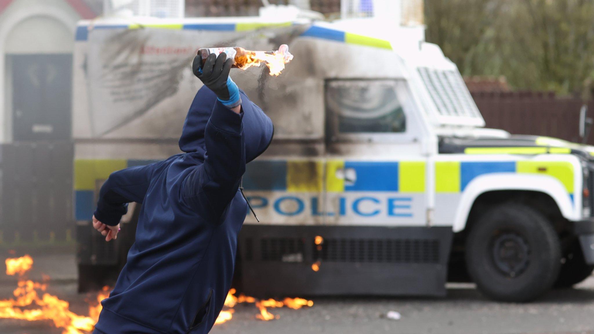 A young man throws a petrol bomb at a police Land Rover