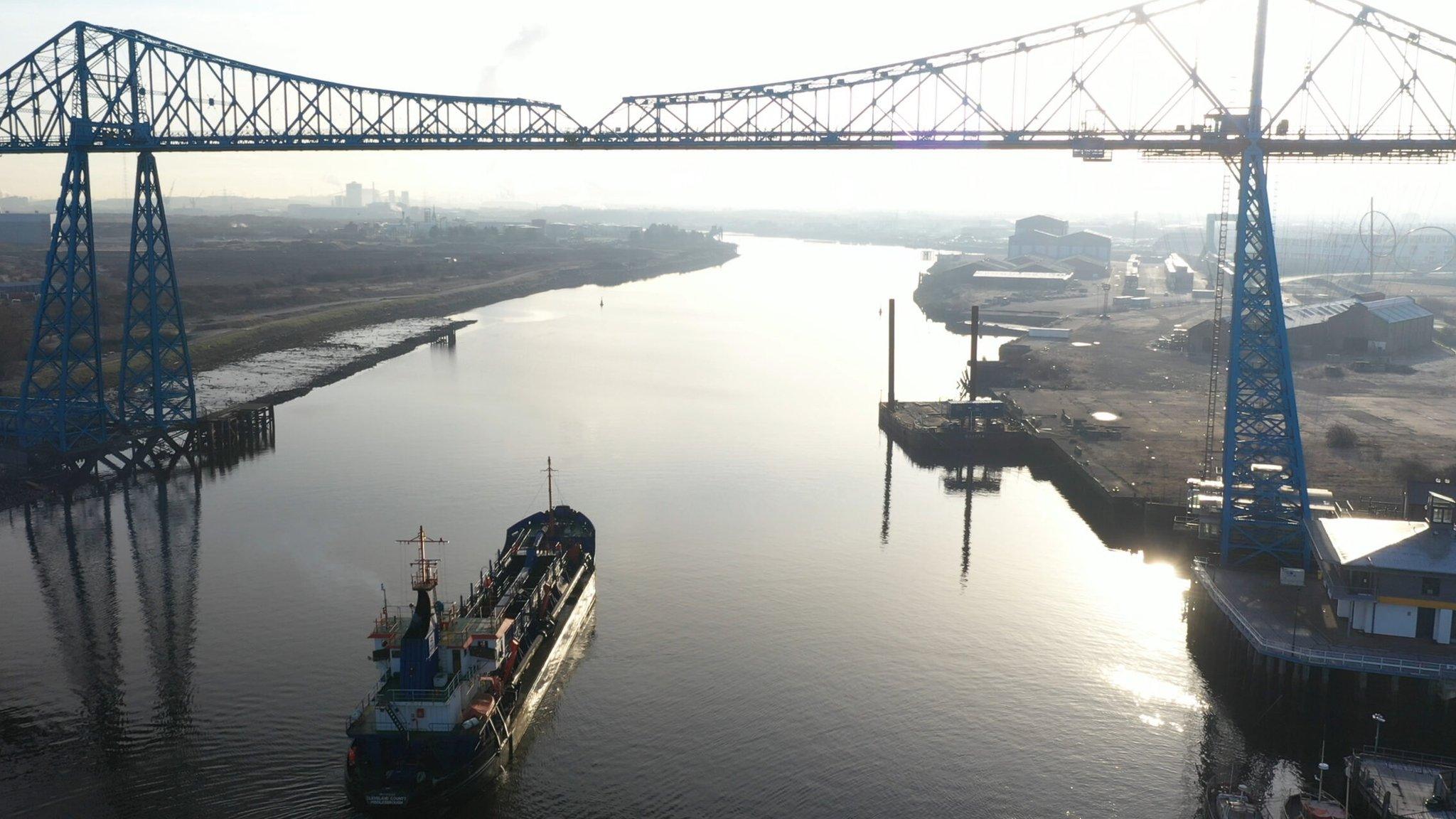 A dredger sails under the Transporter Bridge on the River Tees