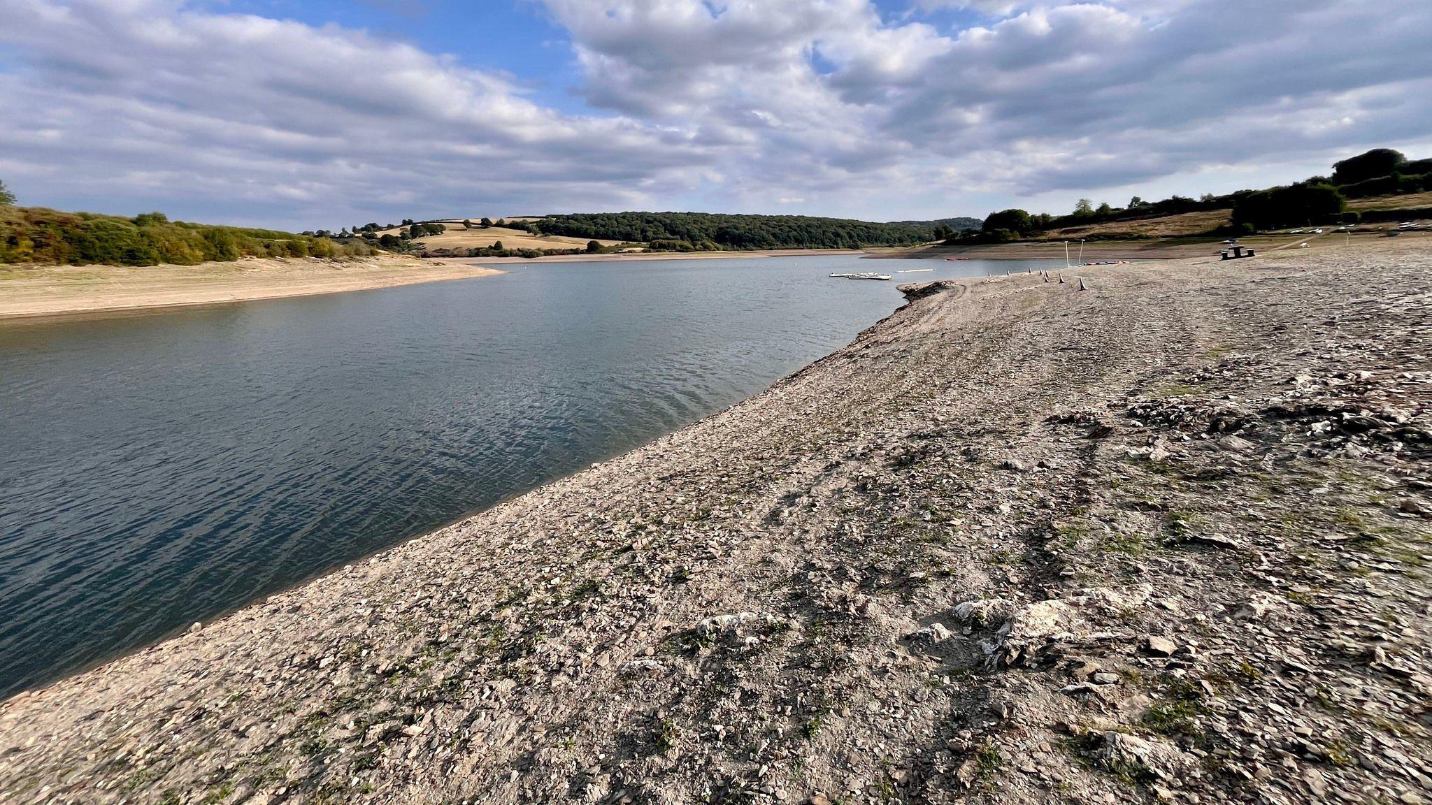 Wimbleball Reservoir pictured when the water level is extremely low. There is a large silt bank exposed on the right, which is usually covered by water as indicated by the algae growth left behind. 