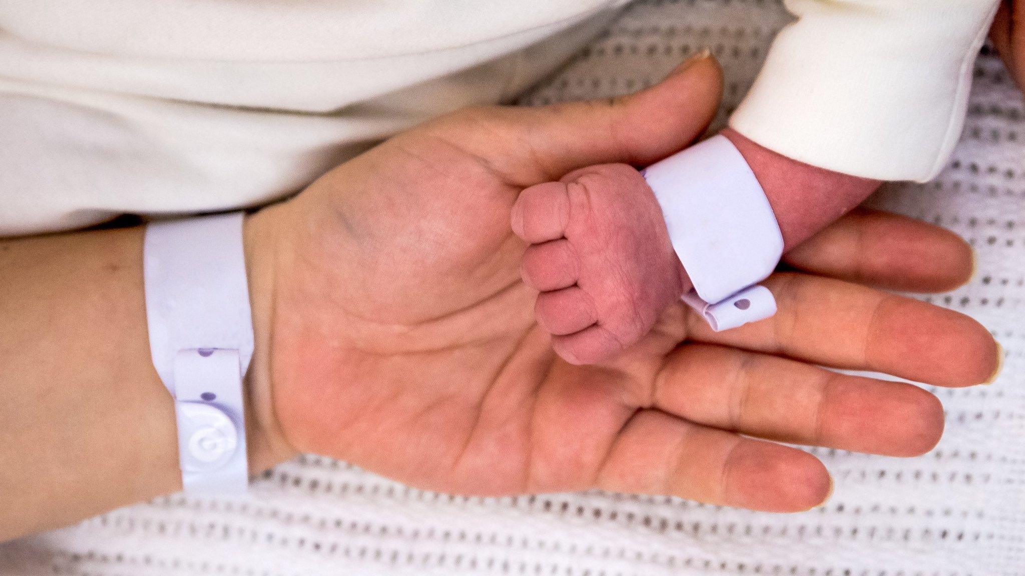 Close-up of hands of newborn and mother