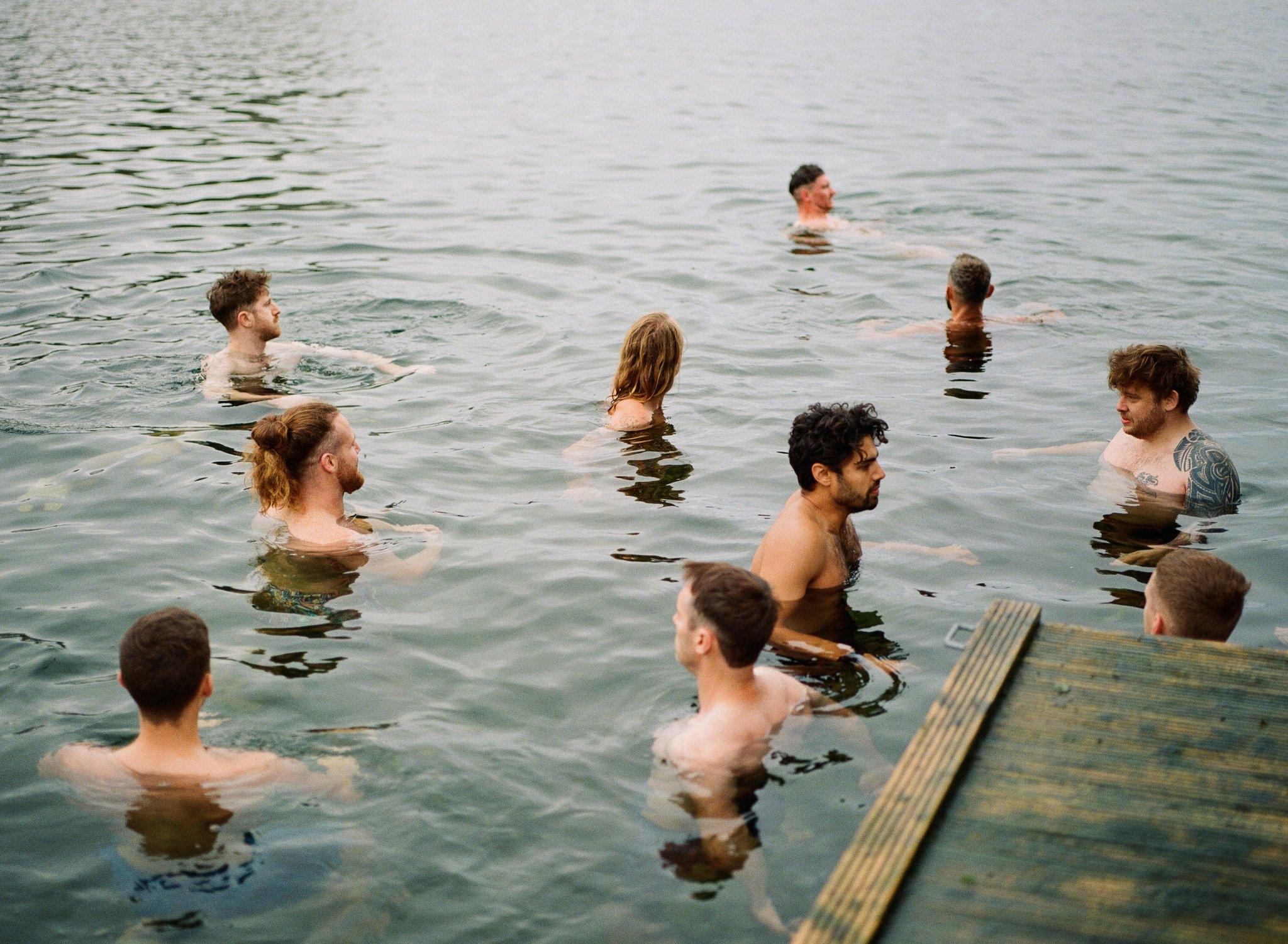 A group of men swim in openwater off a jetty