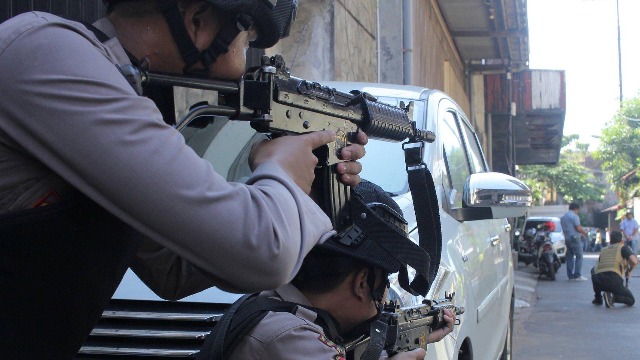 Police aim their weapons at a man who was being searched by other police officers following an explosion at nearby police headquarters in Surabaya, Indonesia May 14, 2018 in this photo taken by Antara Foto