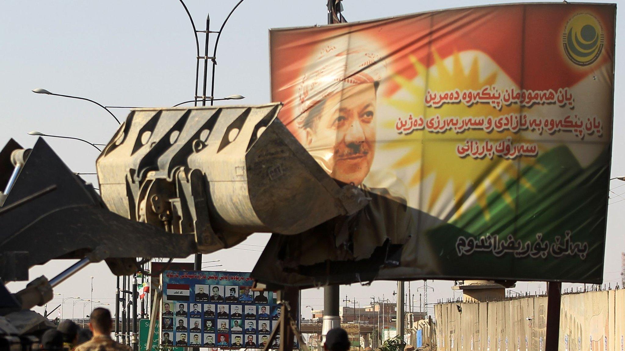 Iraqi forces use a tractor to damage a poster of Iraqi Kurdish president Massud Barzani on the southern outskirts of Kirkuk on October 16, 2017