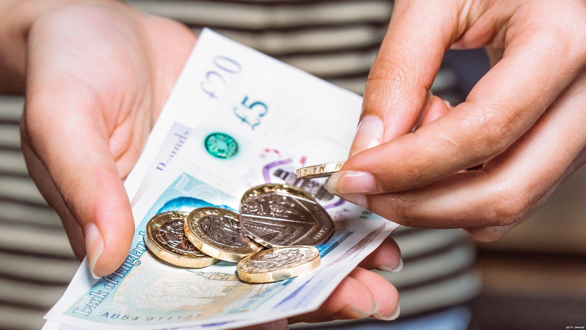 Man holding £5 note and pound coins