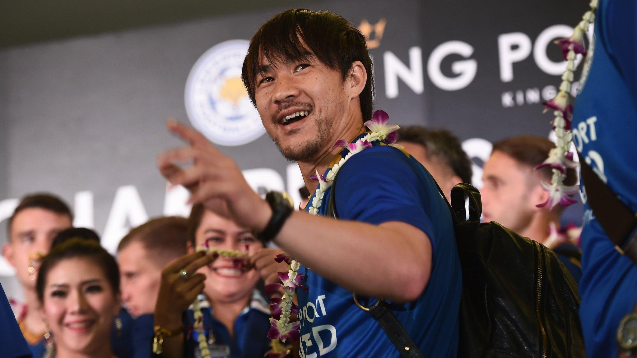 Player Shinji Okazaki, with other players and supporters standing behind him, waves to the press as Leicester City FC players arrive at Suvarnabhumi Airport