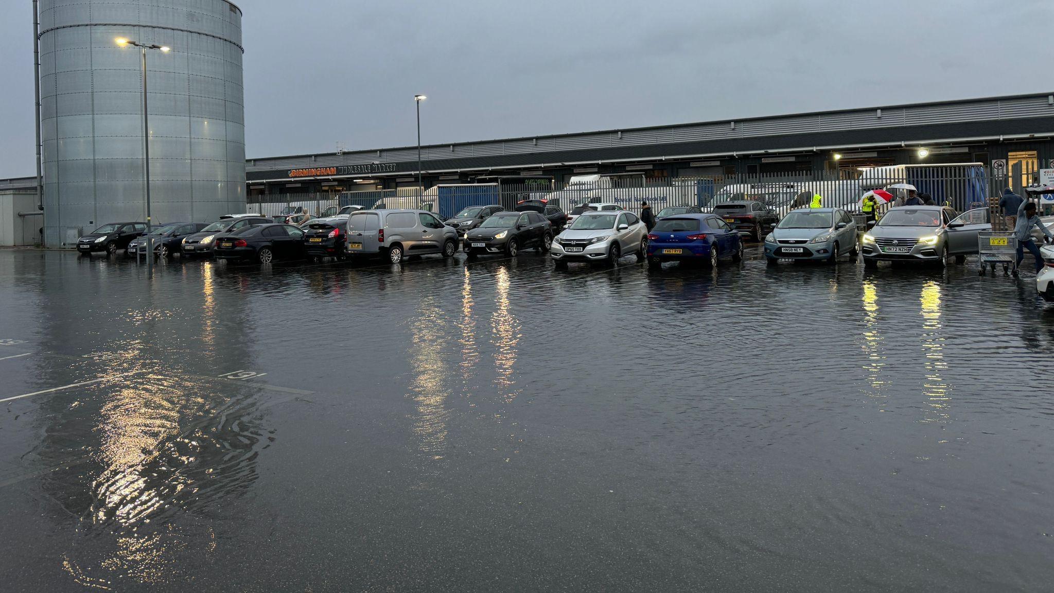 Dozens of cars parked up in a flooded car park 