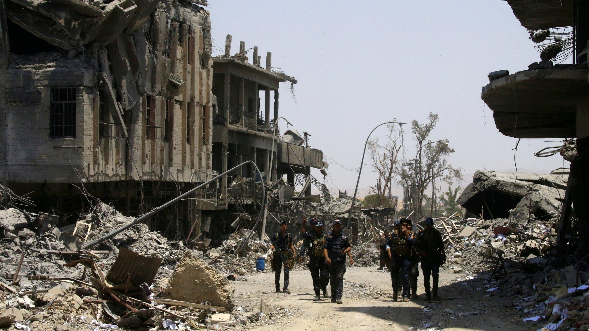 Iraqi security forces walk between destroyed buildings in the Old City of Mosul, Iraq (10 July 2017)