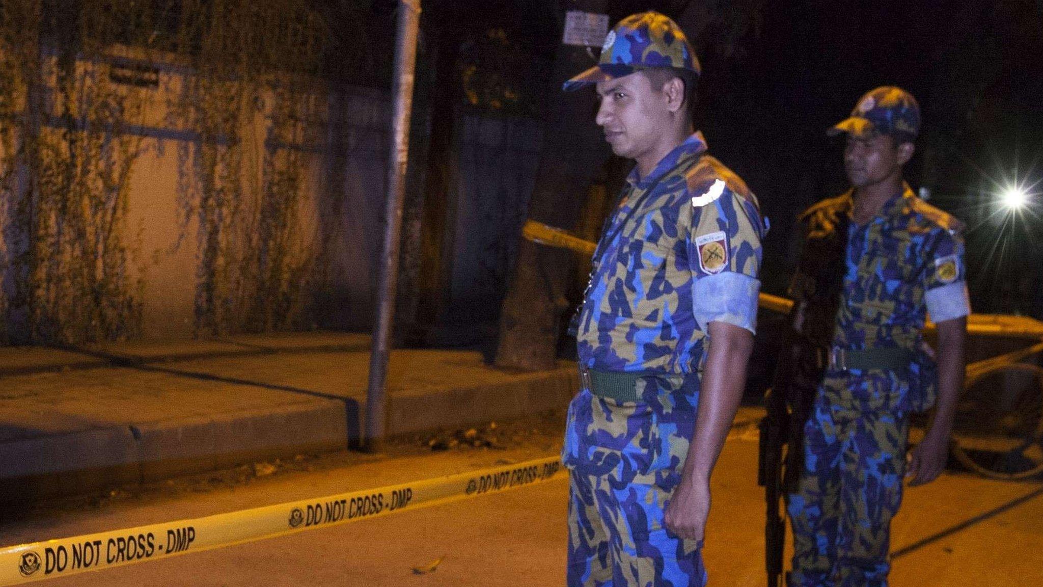 Police officers stand guard at the site where an Italian charity worker has died after being shot by attackers in Dhaka