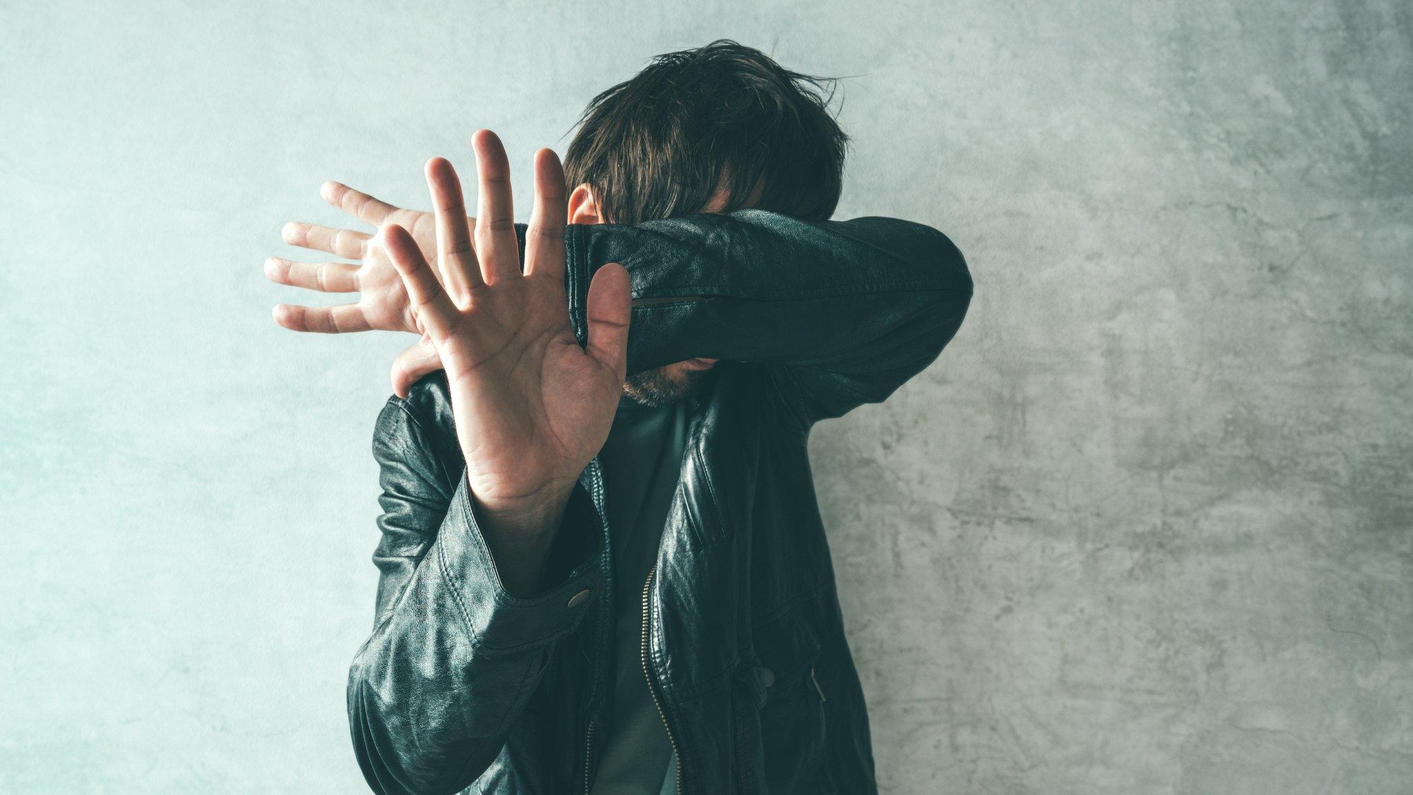 Man covering face with arms