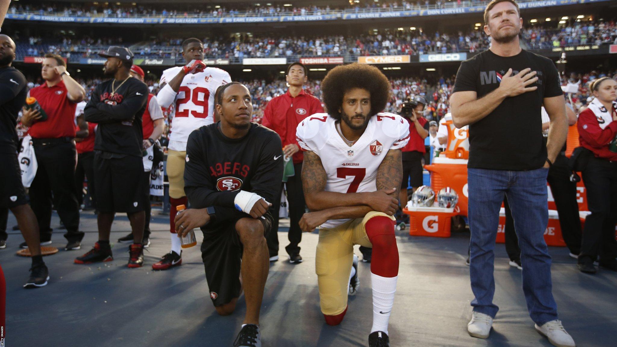 Boyer, (far right) stands with his hand on his heart as the anthem plays. Kaerpernick kneels with team-mate Eric Reid (left)