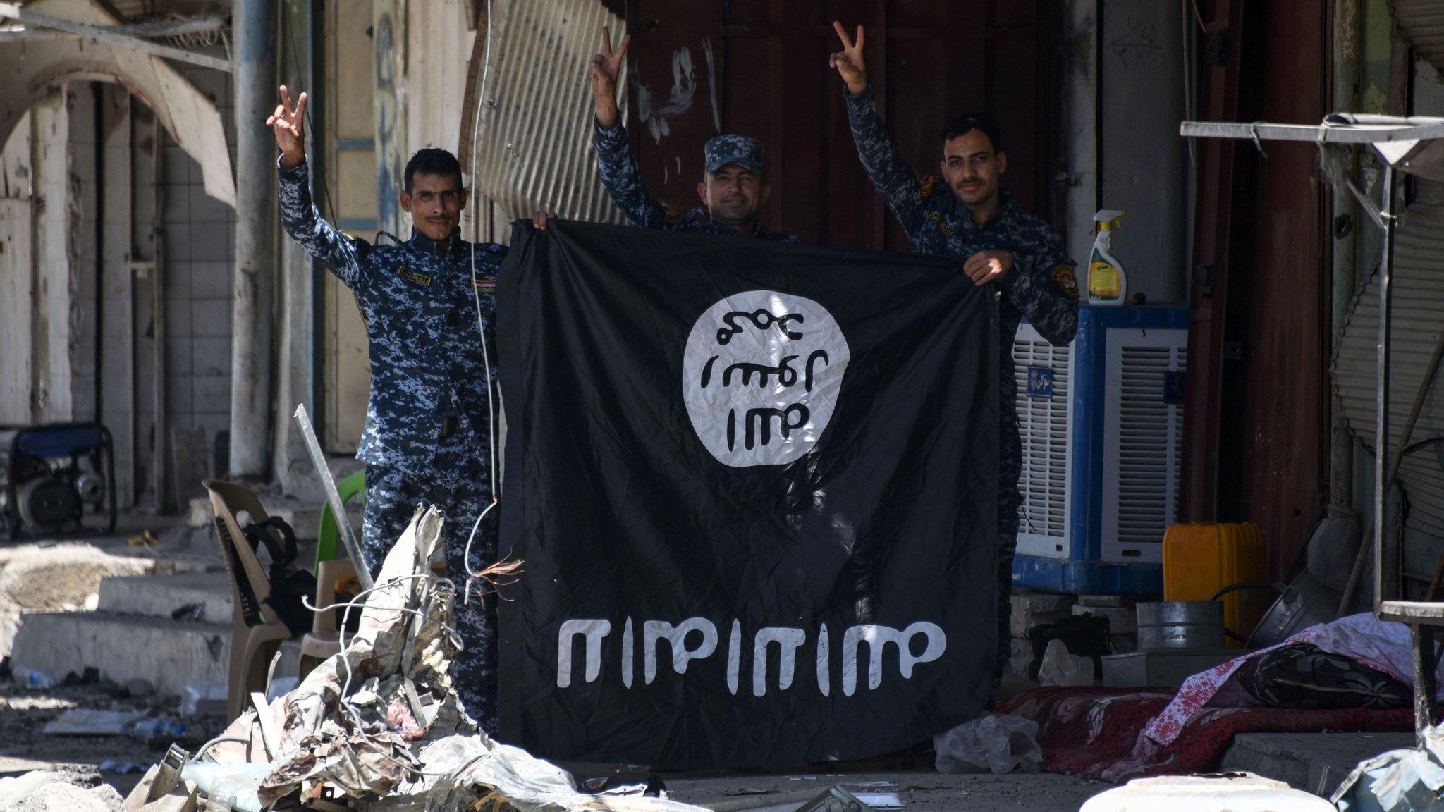 Iraqi government forces flash victory signs while holding an Islamic State (IS) group flag in western Mosul on 9 June 2017