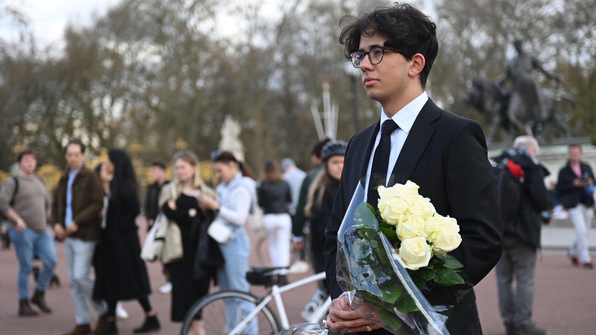 A man holds a bouquet of flowers outside Buckingham Palace on 9 April 2021