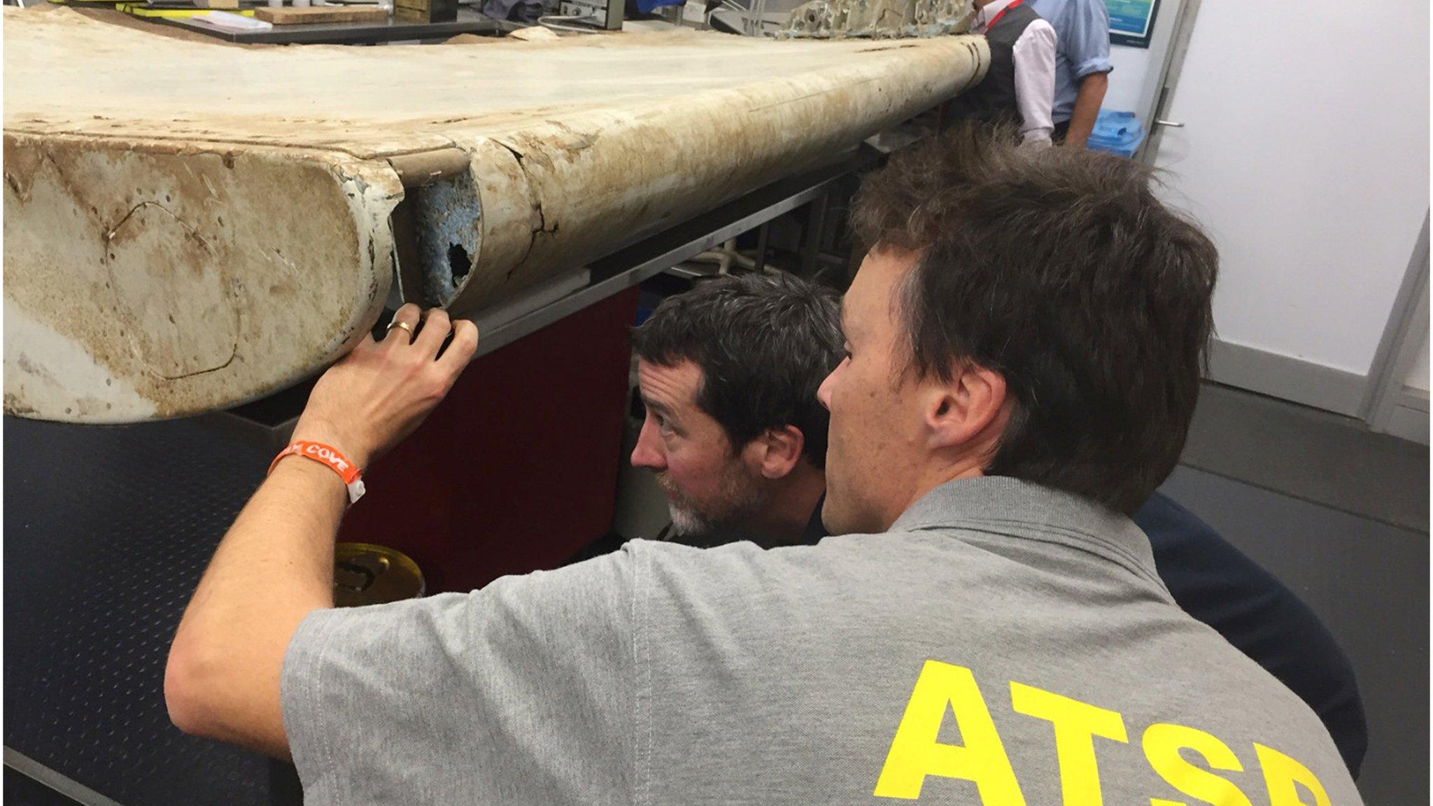 Australian Transport Safety Bureau (ATSB) staff examine a piece of aircraft debris at their laboratory in Canberra, Australia, July. 20, 2016.