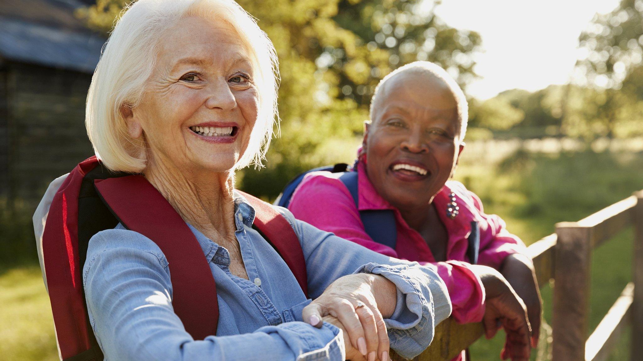 Two female senior friends hiking in countryside