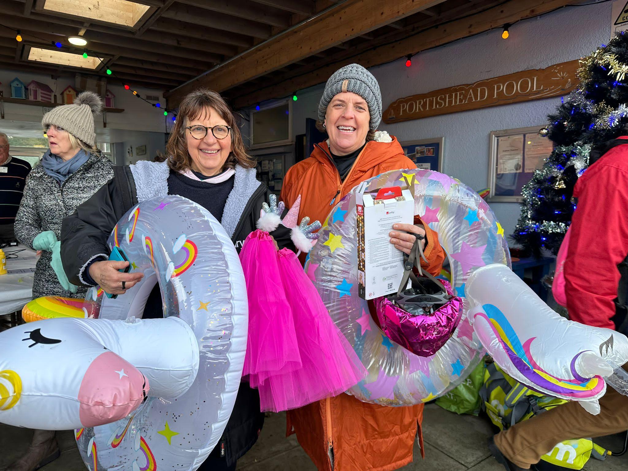 Two women holding inflatable unicorn rings