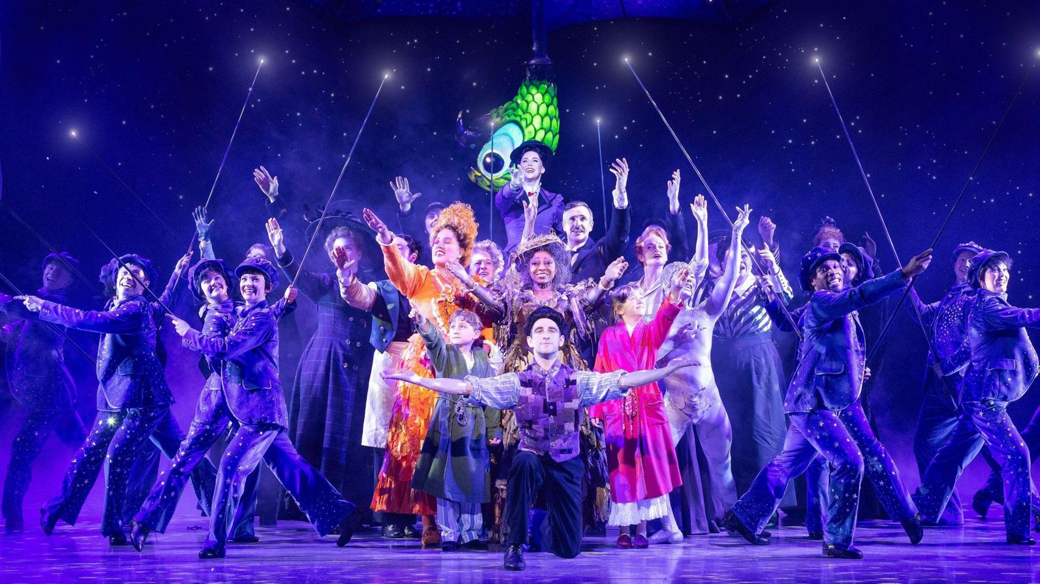 A whole cast photo of the actors in Mary Poppins which is on at the Bristol Hippodrome. There are an assortment of characters including Mary Poppins herself at the top back of the photo, and multiple people dressed as chimney sweeps at the sides