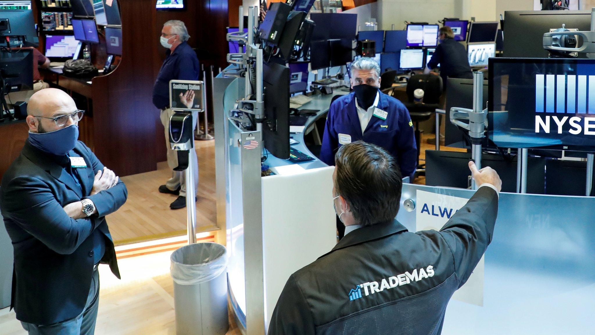 Traders wearing masks work, on the first day of in person trading since the closure during the outbreak of the coronavirus disease (COVID-19) on the floor at the NYSE in New York