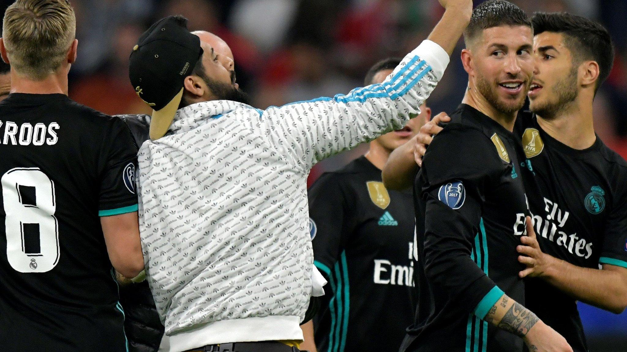 A fan takes a selfie with Real Madrid players after running onto the pitch