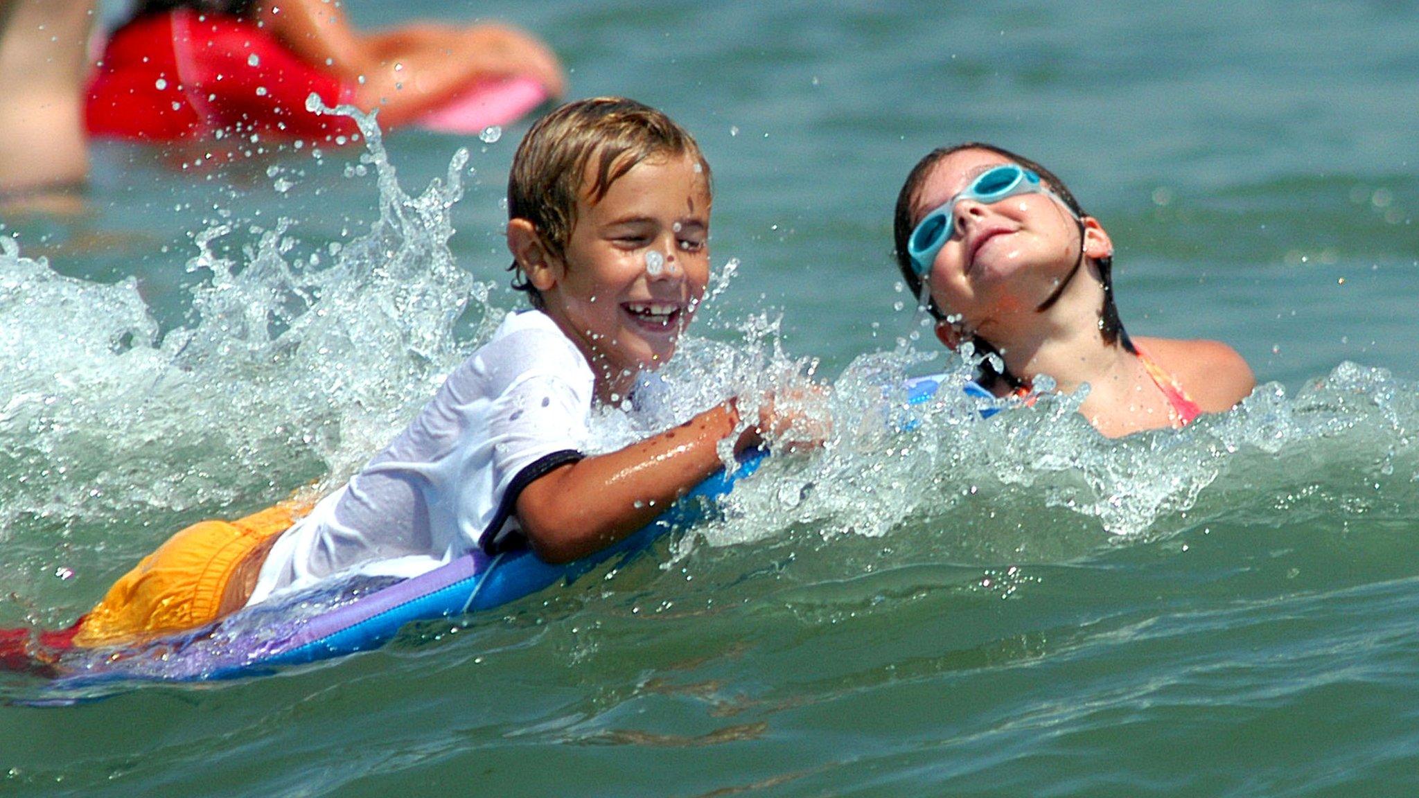 Children play in the surf as they enjoy the cool waters of the Atlantic Ocean