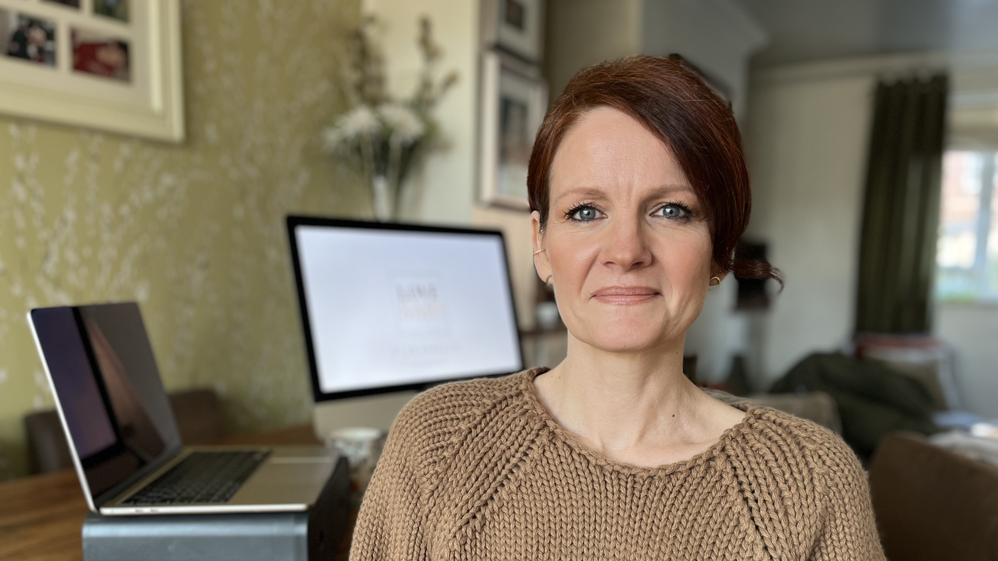 Anna Rowe in a beige jumper sitting by a desk